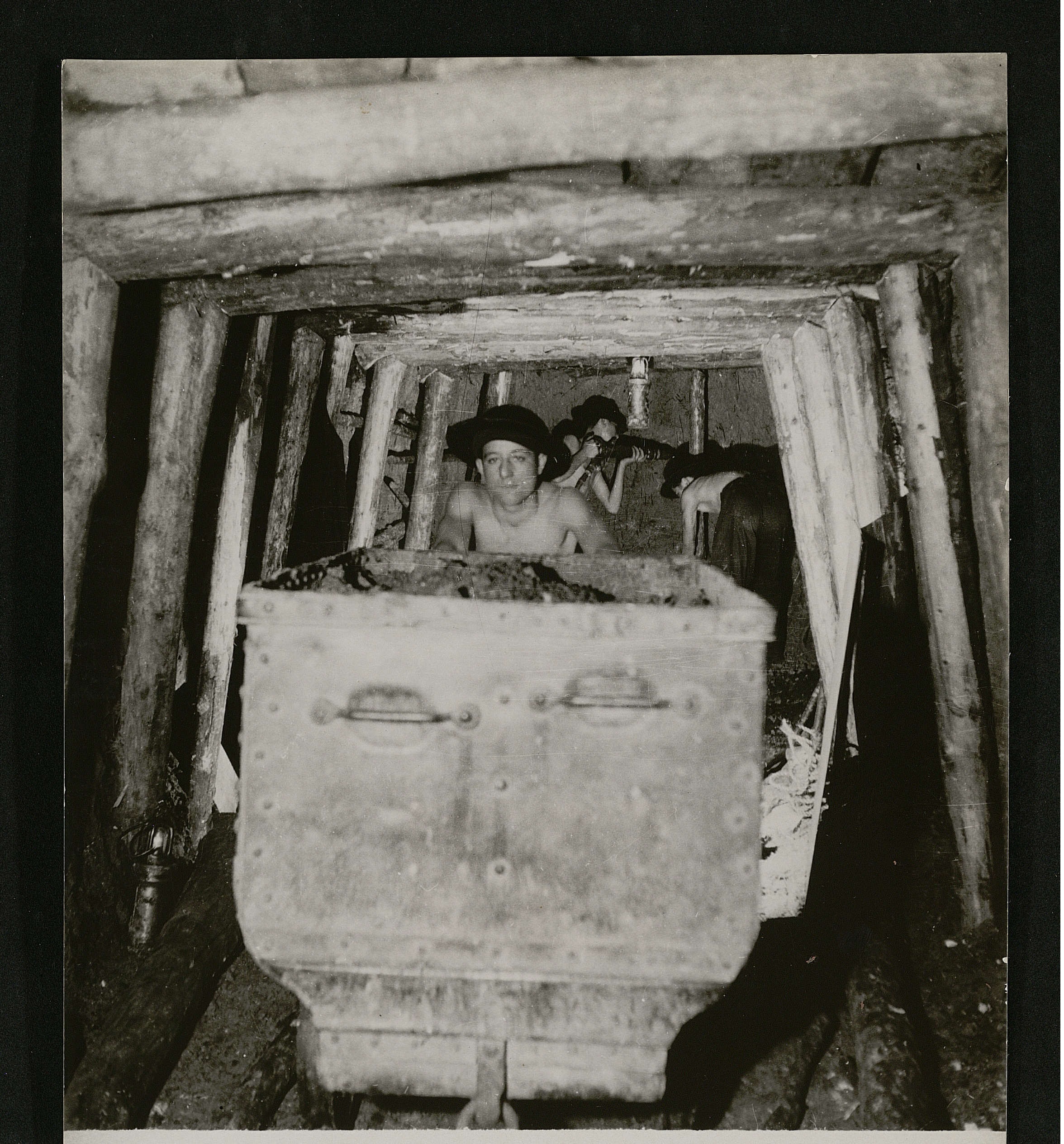 Jeune garçon poussant une berline dans une galerie souterraine : photographie, 1945.