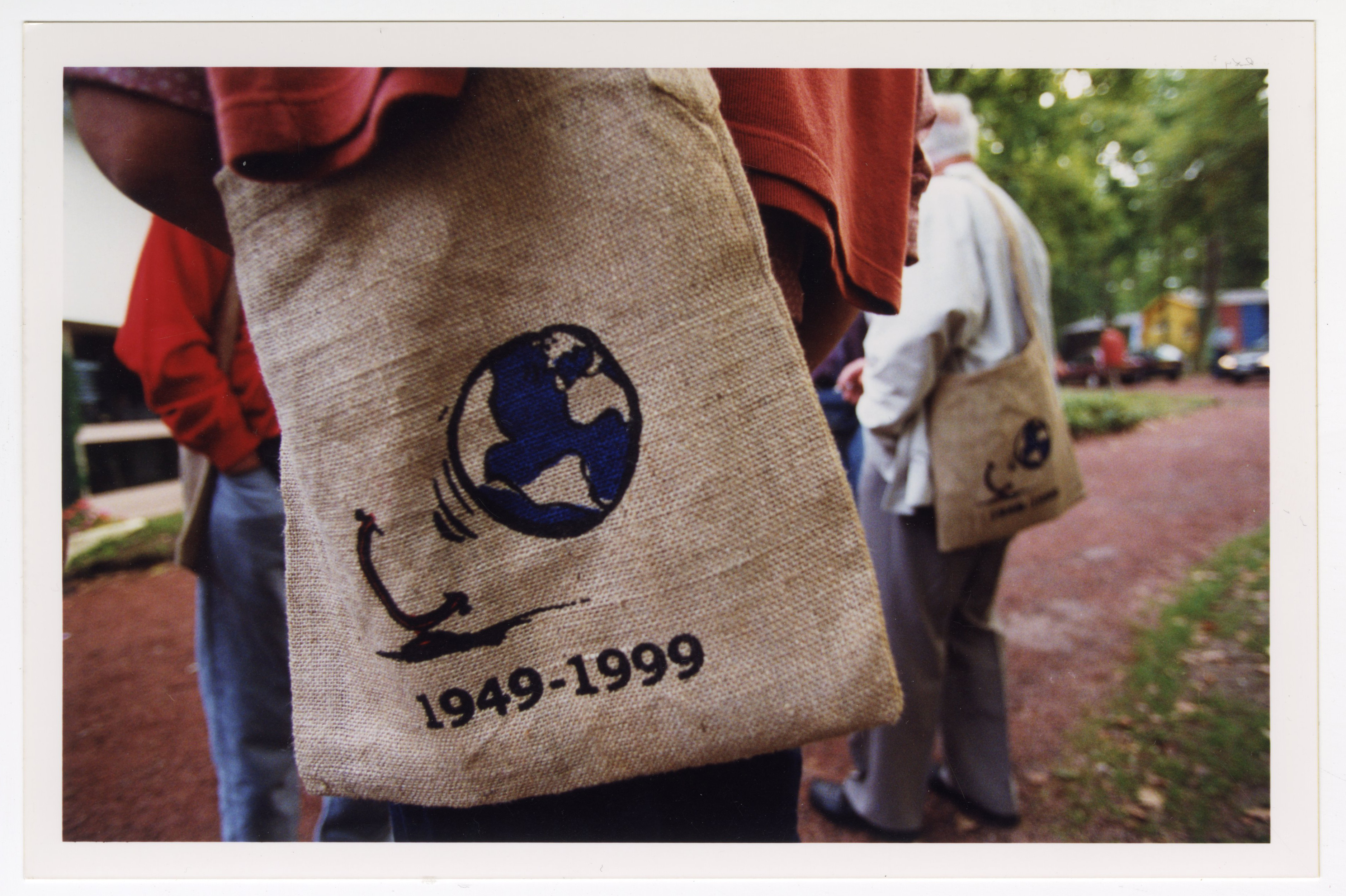 Photographie d'un tote bag avec le logo de l'assemblée Mondiale de 1999, un globe terrestre qui s'échappe de son support. En dessous, les dates ''1949-1999" rappellent le cinquantenaire de la création d'Emmaüs International.