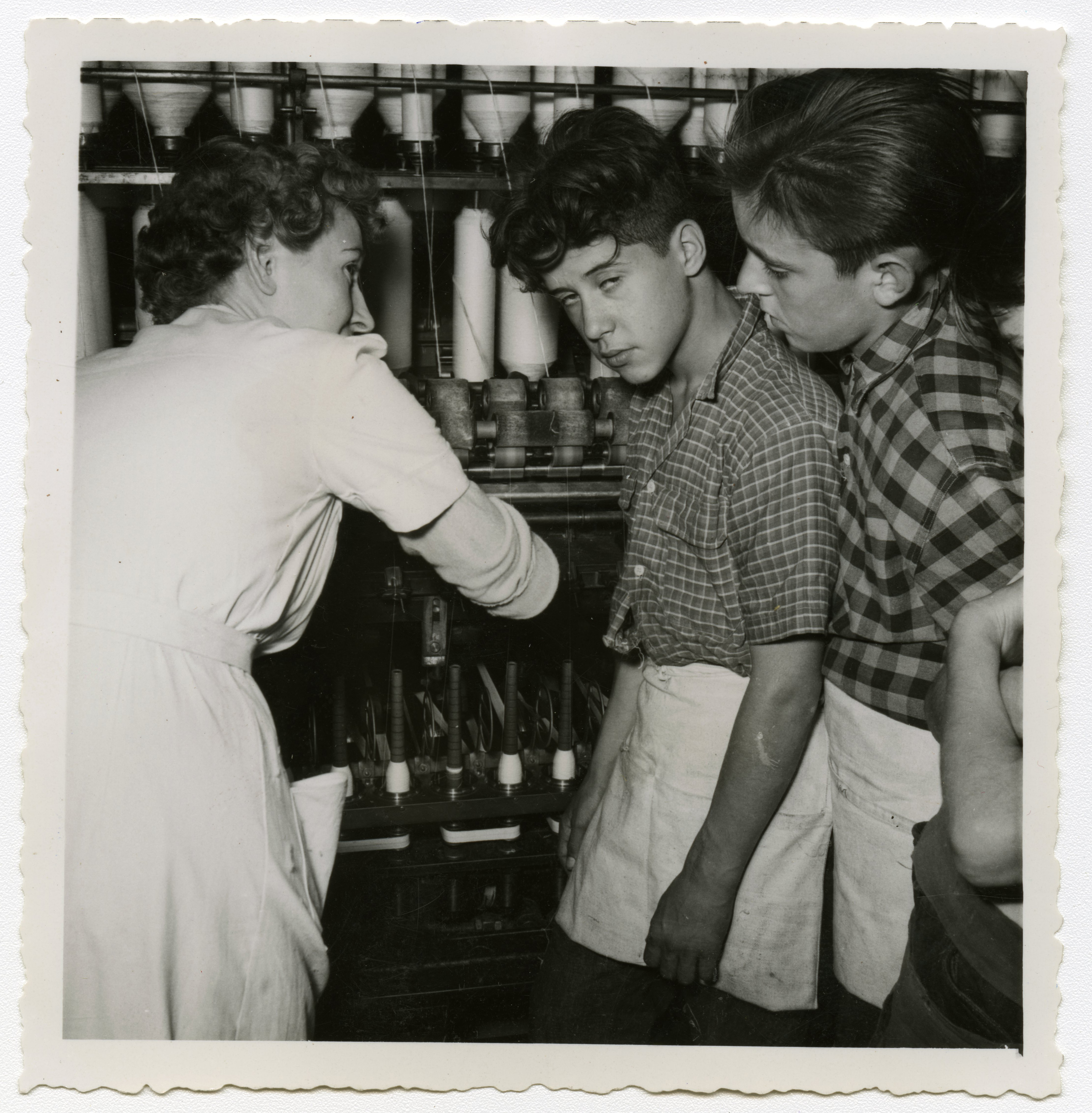 Ouvrière apprenant à de jeunes apprentis le fonctionnement des métiers à tisser : tirage photographique, Lille (Nord), vers 1955.