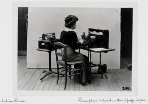 Une femme prend la pose en utilisant une machine à écrire