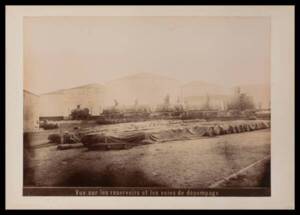 Vue extérieure des réservoirs avec fûts de bois et wagons-citernes de la Société commerciale et industrielle de Naphte Caspienne et de la Mer Noire, tirage photographique noir et blanc, 1896.
