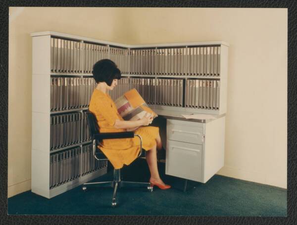 Une femme pose devant un meuble &agrave; classeurs, s.d. ANMT 2002 6 22, Ron&eacute;o (fabricant de duplicateurs, de mat&eacute;riels et mobilier bureau).