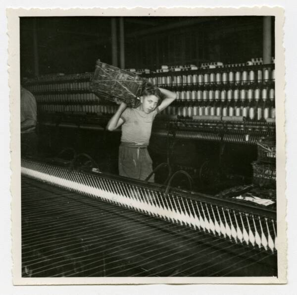 Un jeune apprenti circule dans une filature, années 1950.